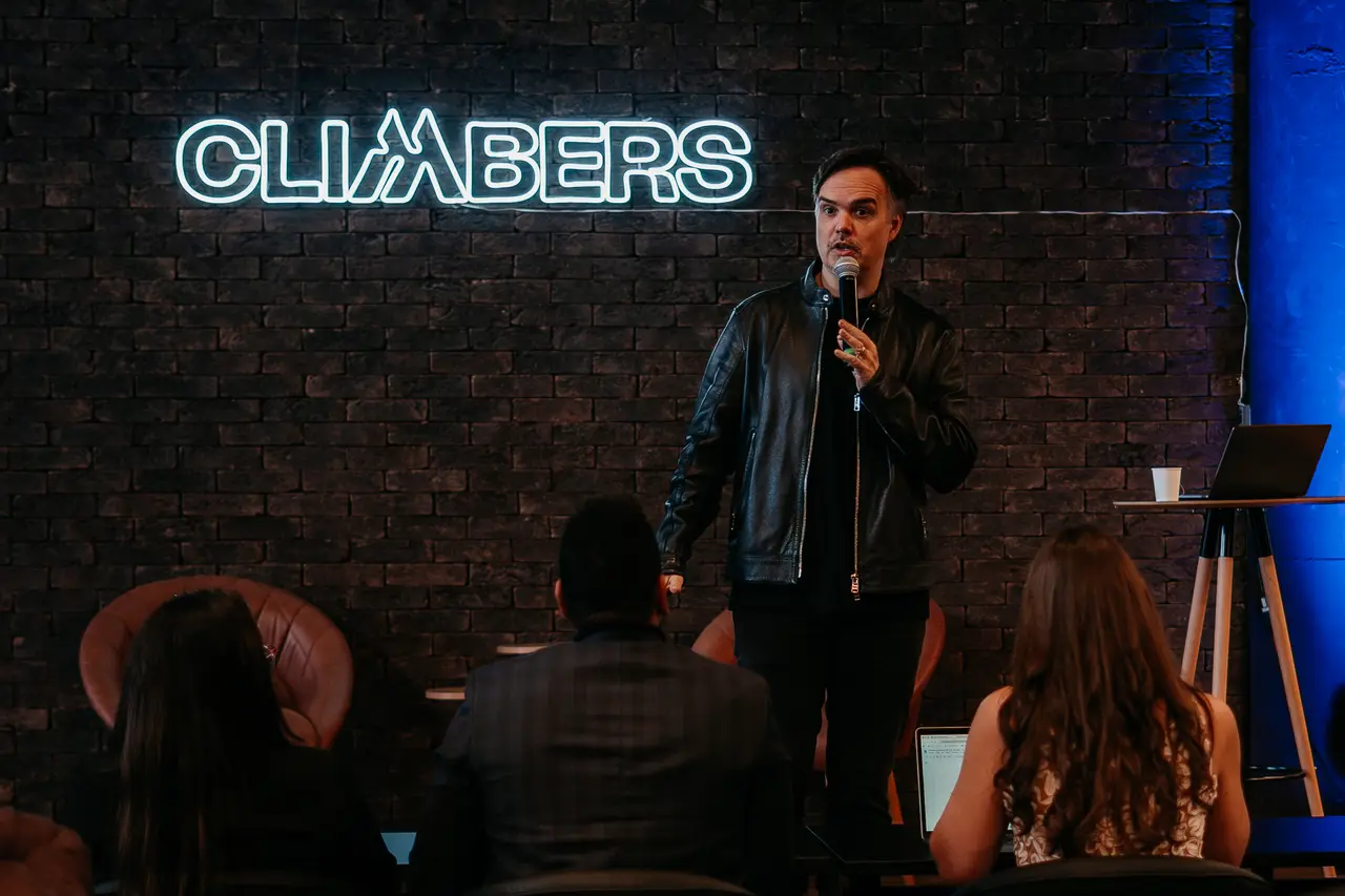 Palestrante no palco em frente ao neon Climbers