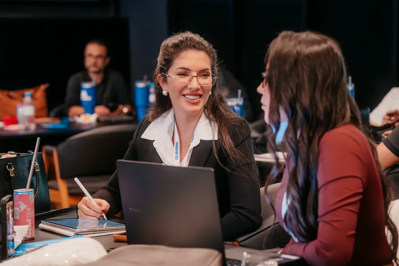 Participantes conversam e riem nas mesas do evento
