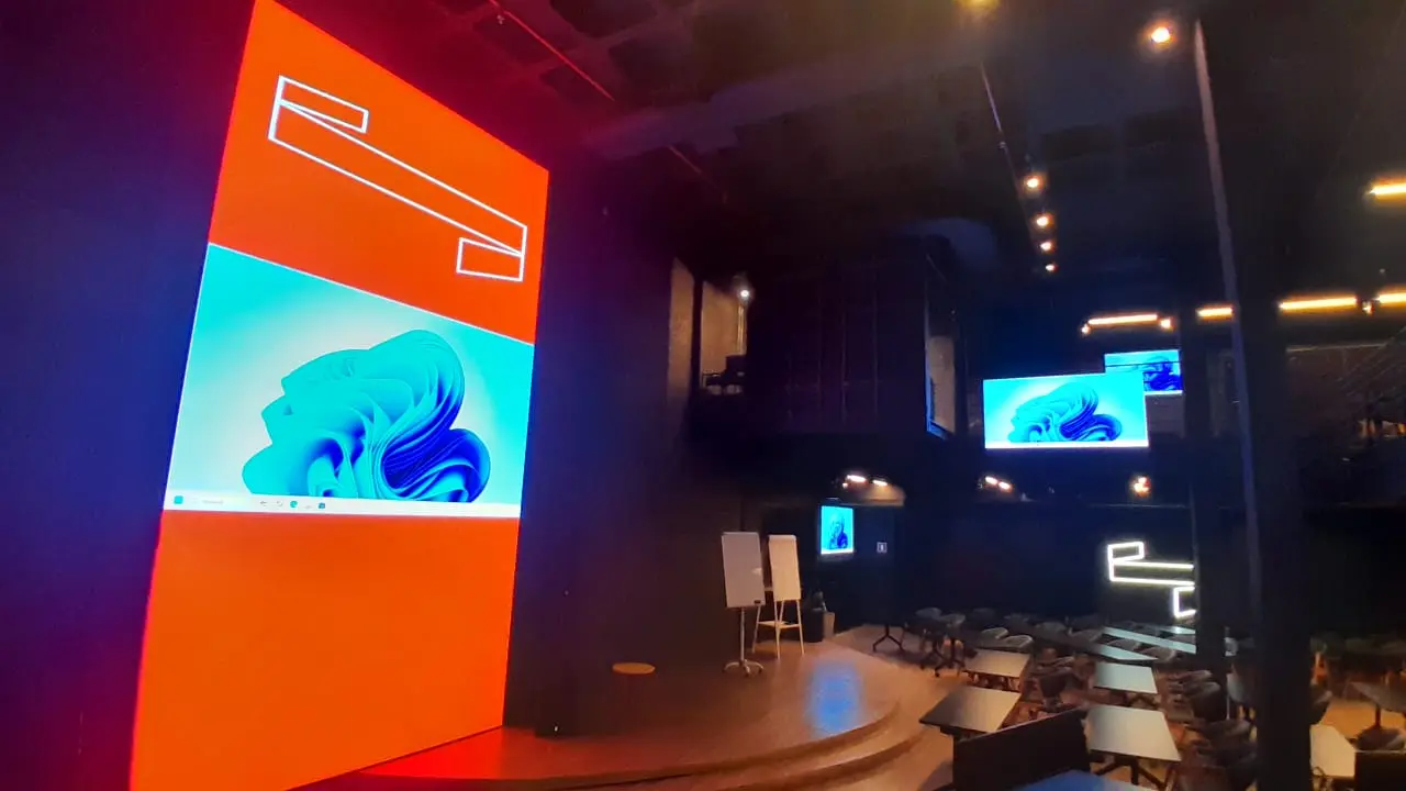 Painel de LED laranja no palco e monitores na sala
