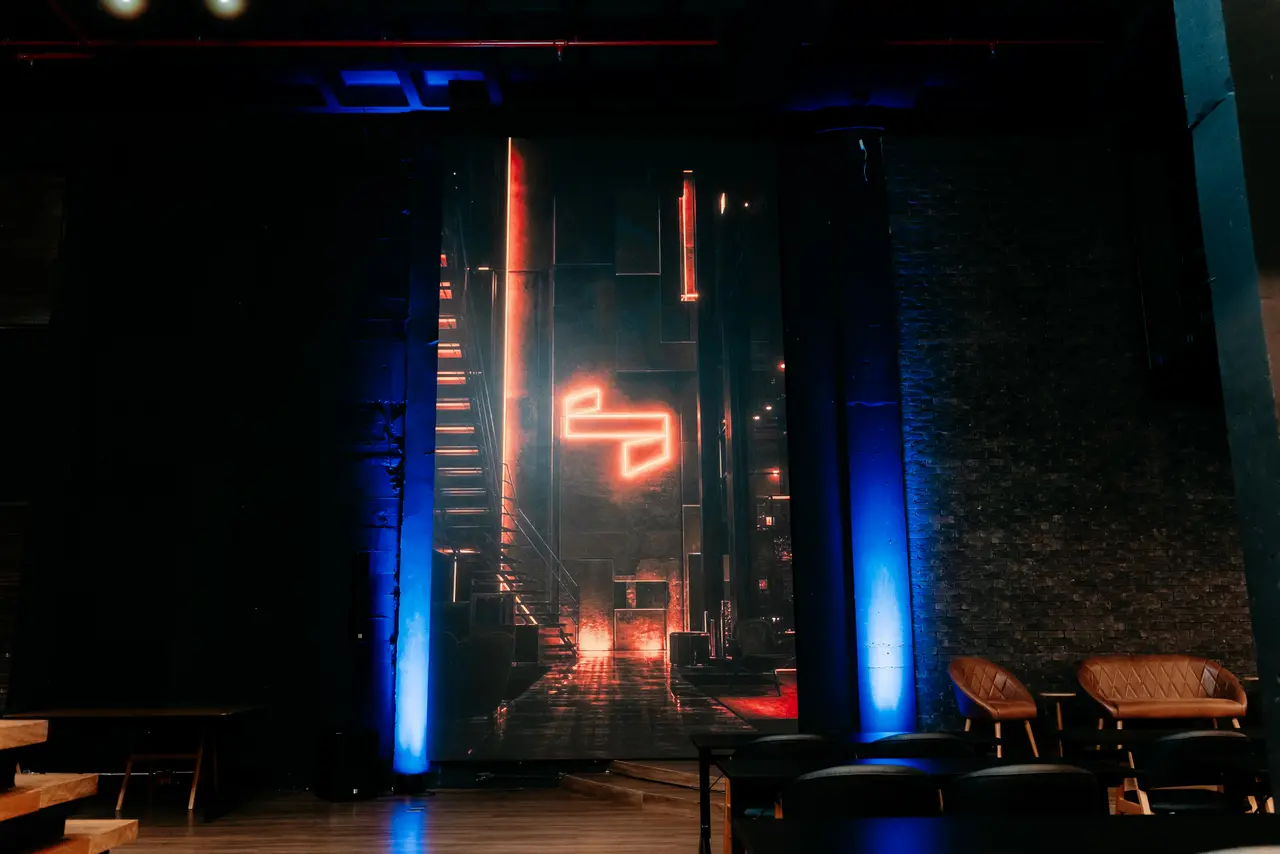 Palco da Casa com o neon vermelho entre colunas de luz azul