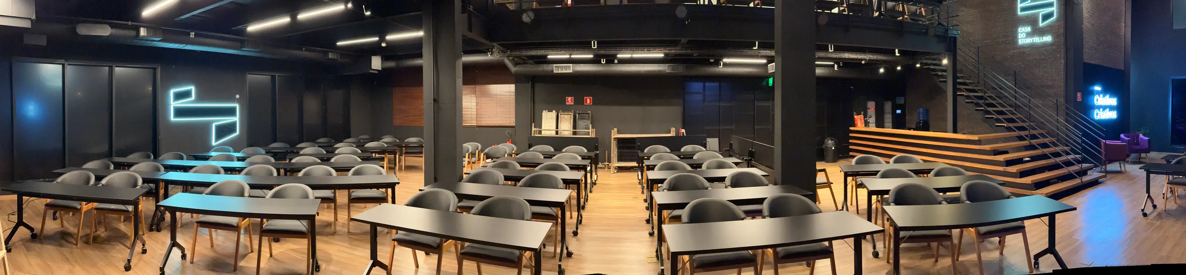 Panorâmica do térreo com as mesas em formato escolar, de uma parede à outra