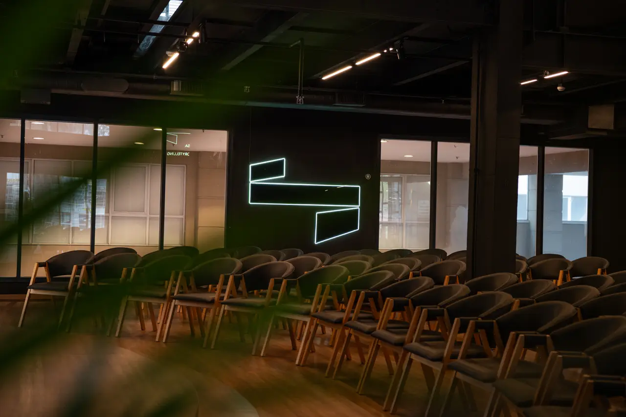 Neon da Casa entre plantas, com a sala ao fundo